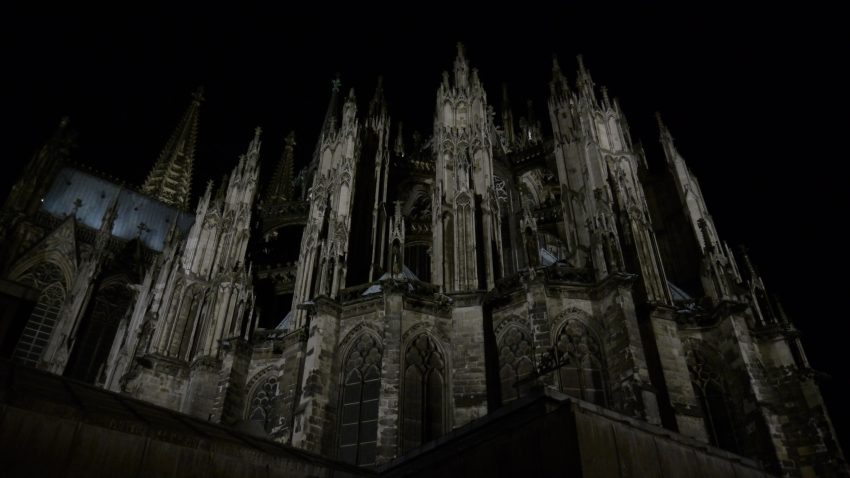 An upward shot of a gothic cathedral silhouetted against the dark night sky.